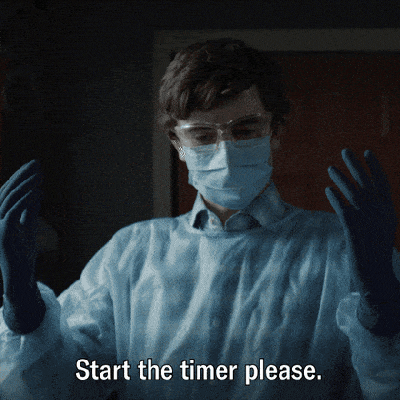 A surgeon in gloves and mask saying start the timer please